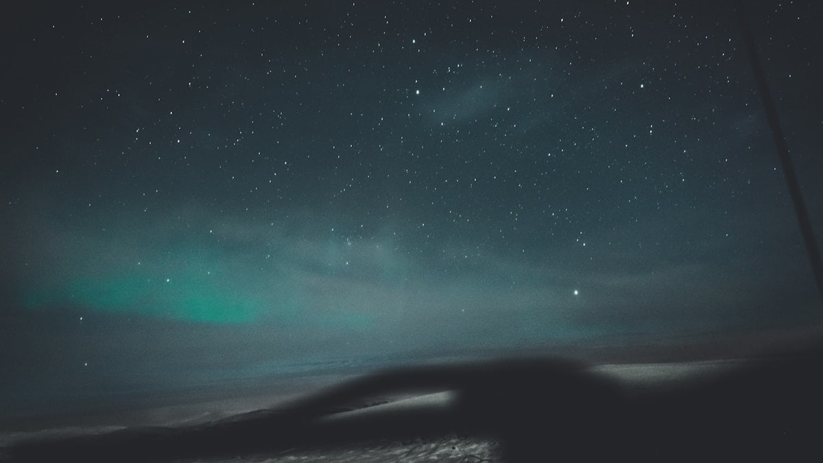 a night sky with stars and a green light